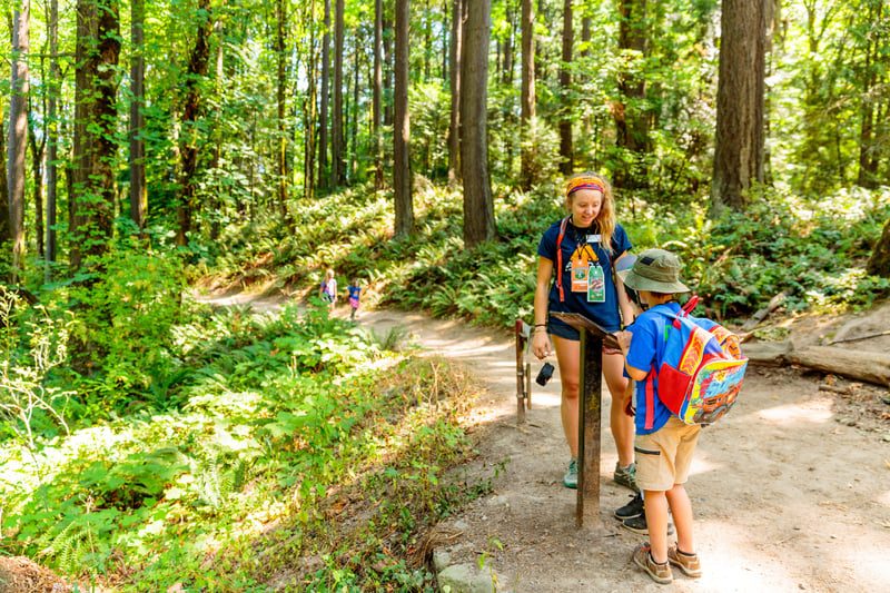 summer camp counselor looking at map with camper