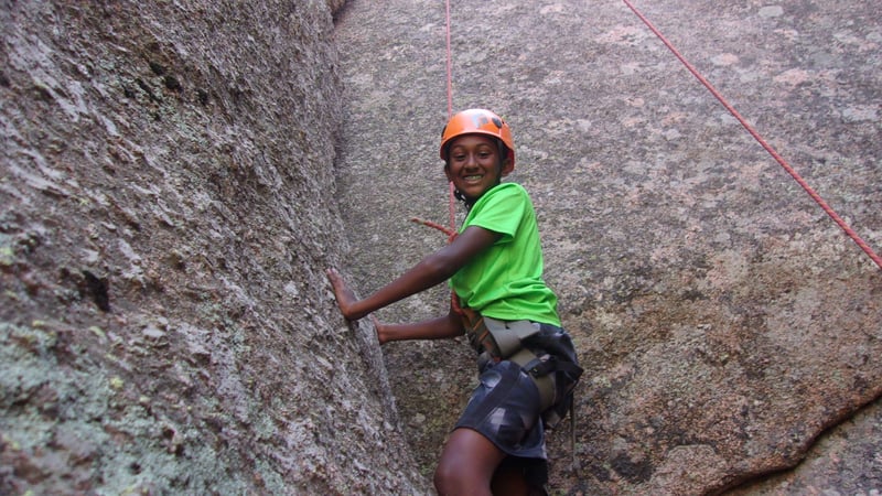 child smiling while rock climbing