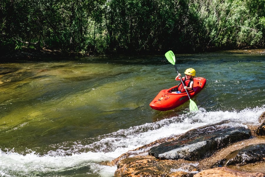 young girl whitewater kayaking about to reach a rapid