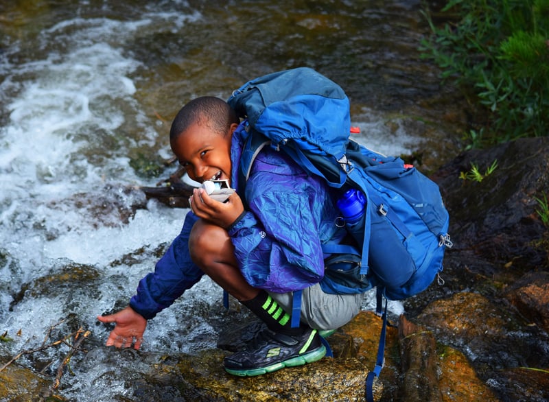 child on a backpacking trip near a river